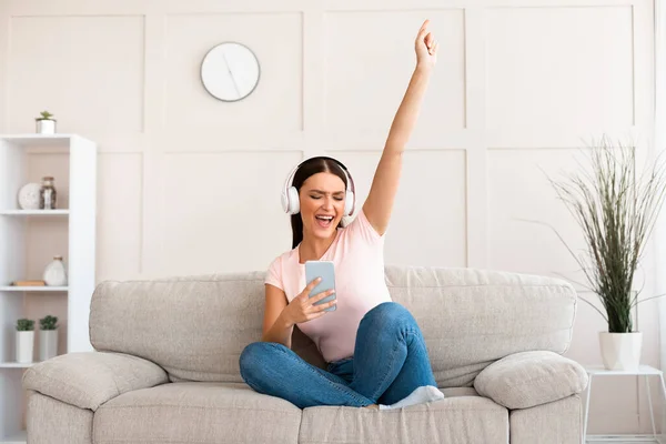 Kvinnan lyssnar musik i hörlurar har roligt sitter hemma — Stockfoto