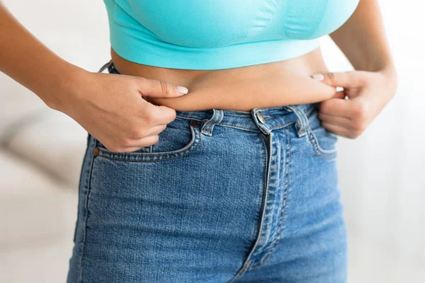 Unrecognizable Woman Touching Drooping Stomach After Weight Gain At Home