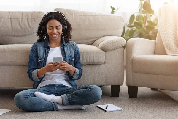 Μαύρο Millennial κορίτσι ακούγοντας μουσική με Smartphone και ακουστικά στο σπίτι — Φωτογραφία Αρχείου