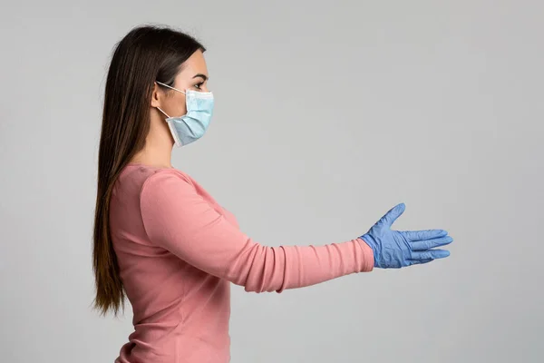Jonge vrouw in medische masker en handschoenen geven hand voor handdruk — Stockfoto