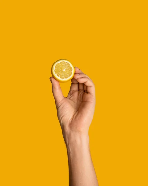 Close up de mão masculina segurando limão suculento no fundo laranja, panorama — Fotografia de Stock