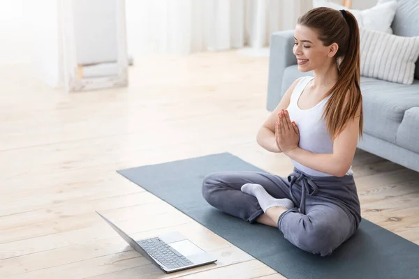 Junge Frau praktiziert Yoga zu Hause mit Laptop — Stockfoto