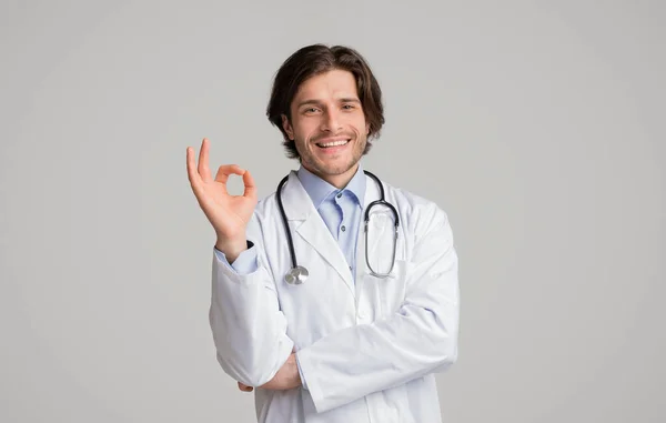 Positieve mannelijke arts in medische jas vertoont ok teken — Stockfoto