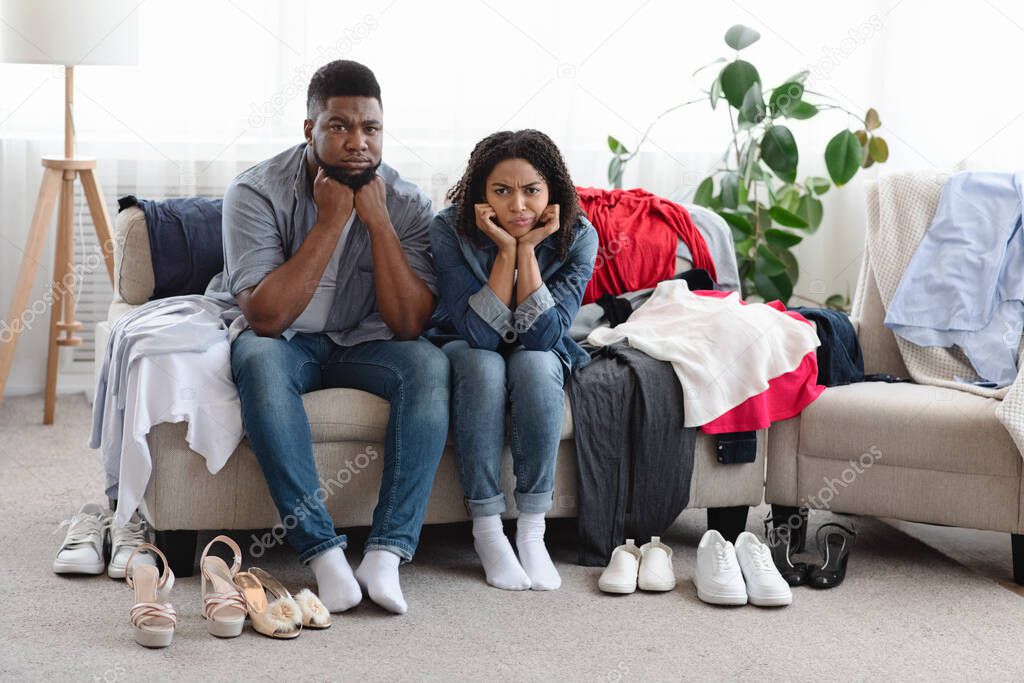 Upset Black Couple Sitting On Couch Beside Old Fashioned Unfitting Clothes