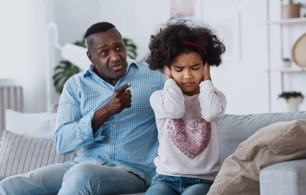 Family conflict caused by coronavirus isolation. Angry granddad and his granddaughter closing her ears indoors — Stock Photo, Image