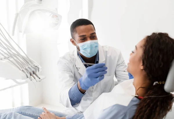 Dentista afro-americano fazendo tratamento na clínica moderna — Fotografia de Stock