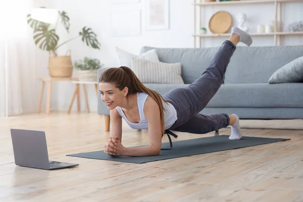 Sportliches Mädchen übt zu Hause mit Laptop — Stockfoto