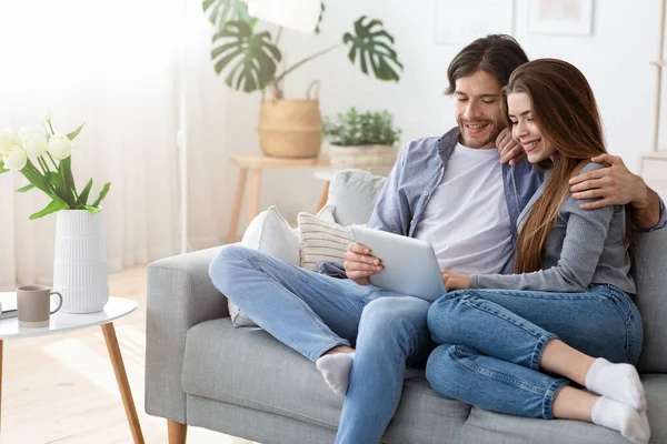 Pareja positiva de compras en línea en casa, utilizando tableta digital —  Fotos de Stock