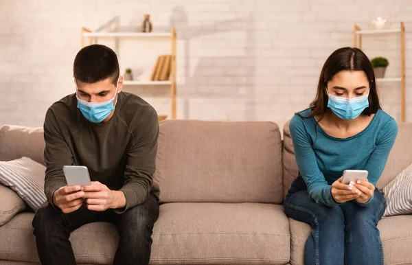 Cuplu purtând mască chirurgicală folosind telefoane mobile — Fotografie, imagine de stoc