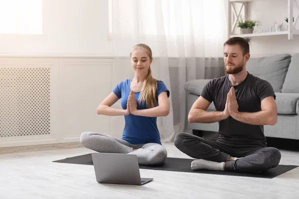 Молодая пара, практикующая йогу с инструктором онлайн — стоковое фото