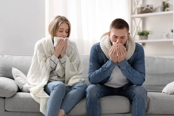 Sick man and woman coughing at home interior