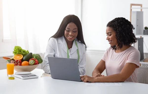 Zwarte vrouwen voedingsdeskundige en patiënt op zoek naar laptop scherm — Stockfoto