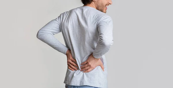 Kidney pain concept. Man presses hands to his back