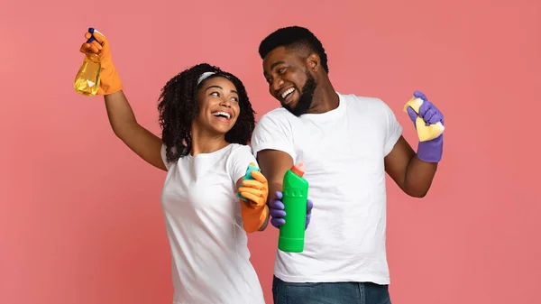 Fröhliches afrikanisches Paar mit Haushaltsgegenständen in der Hand vor rosa Hintergrund — Stockfoto