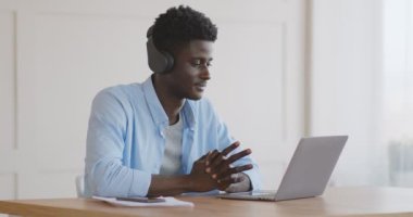 Genç Afrikalı bir adam dizüstü bilgisayarında iş görüşmesi yapıyor.