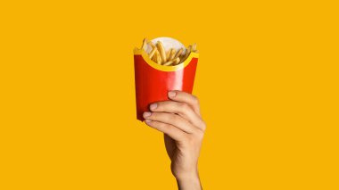 KHARKIV, UKRAINE - 4 Nisan 2020: Turuncu arka planda McDonalds 'dan küçük bir paket patates kızartması gösteren adam