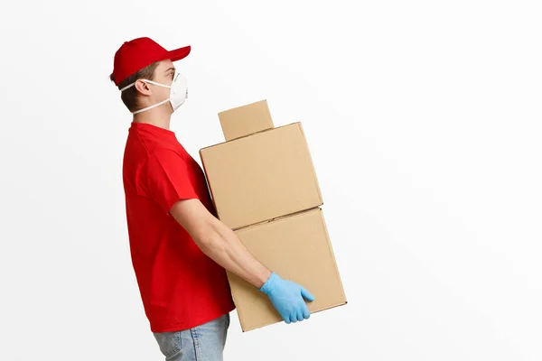 Entrega hombre en mascarilla facial y guantes sostienen cajas de cartón — Foto de Stock