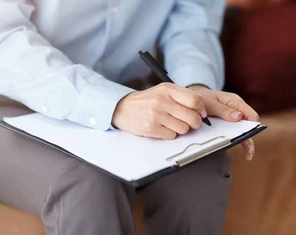 Psicólogo profesional irreconocible tomando notas sentado en el sofá en el cargo — Foto de Stock