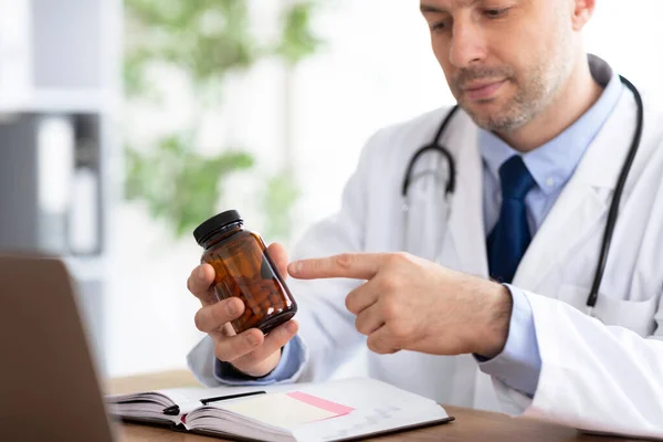 Mature experienced doctor holding jar for pills — Stock Photo, Image