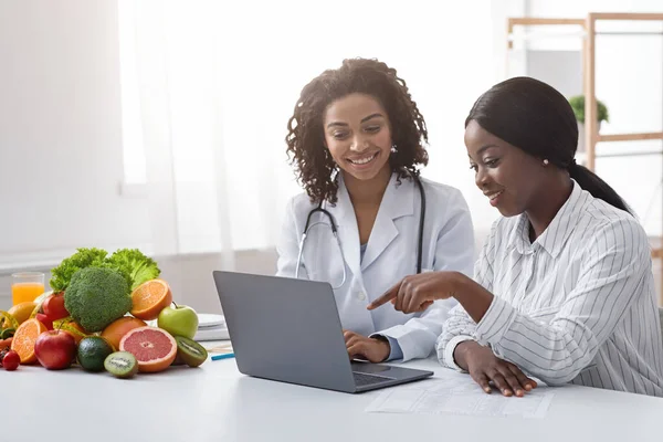 Αφρικανικές γυναίκες διαιτολόγος και ασθενής κοιτάζοντας οθόνη laptop — Φωτογραφία Αρχείου