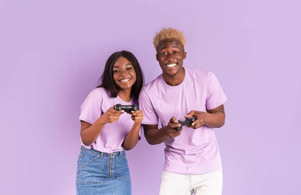 幸せなアフリカ系アメリカ人カップルとともにジョイスティックはライラックの背景にビデオゲームをプレイ — ストック写真