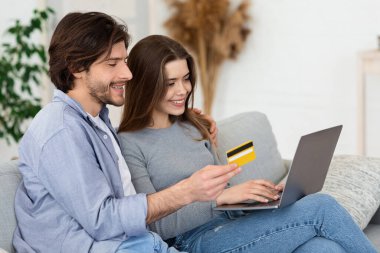Kredi kartı ve dizüstü bilgisayarı olan kadın ve erkek online alışveriş yapıyor.