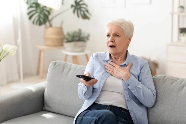 Ειδήσεις Coronavirus. Σοκαρισμένη ηλικιωμένη γυναίκα βλέποντας τηλεόραση στο σπίτι — Φωτογραφία Αρχείου
