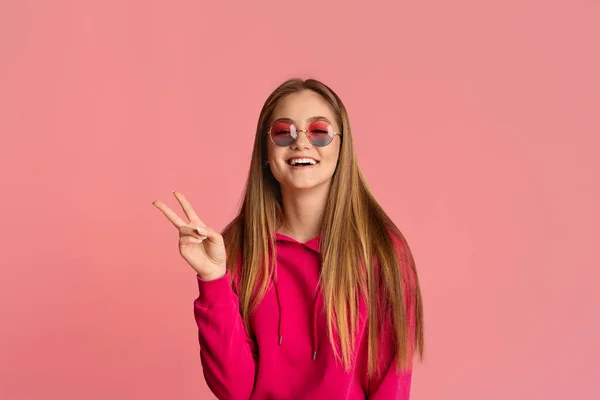 Adolescente chica en gafas de color rosa muestra signo de paz — Foto de Stock