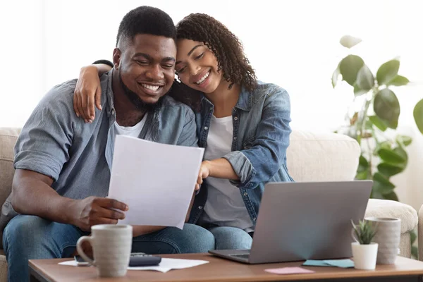 Familienversicherung. Schwarzes Paar liest Dokumentation zu Hause und überprüft Vereinbarung gemeinsam — Stockfoto