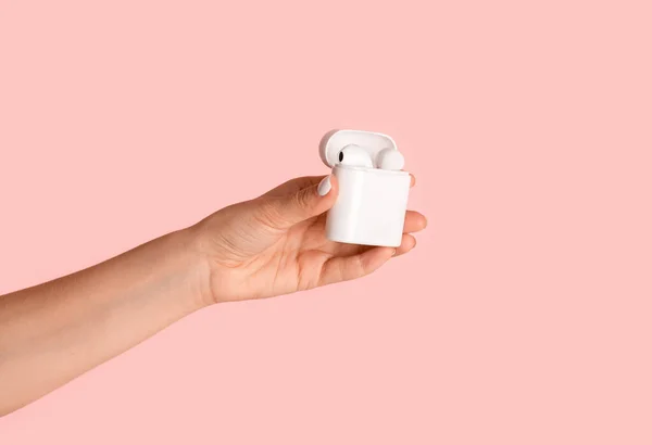 Millennial Girl zeigt Box mit modernen Ohrhörern auf rosa Hintergrund, Nahaufnahme der Hand — Stockfoto