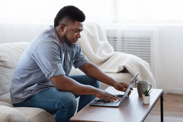 African Man Disinfecting Laptop Keyboard With Wipes Before Work At Home