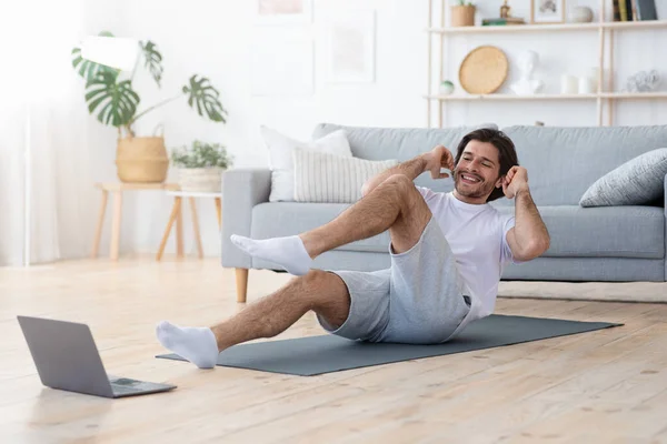 집에서 운동을 하고 노트북 화면을 보는 긍정적 인 남자 — 스톡 사진