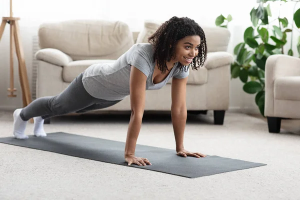 Das häusliche Training. Junge sportliche schwarze Frau macht Plank-Übung zu Hause — Stockfoto