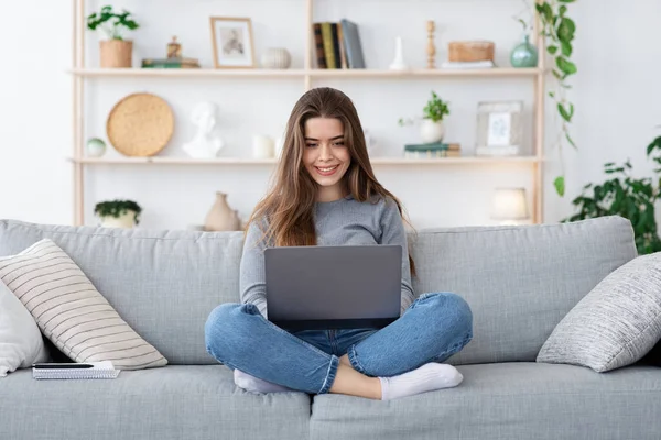 Chica positiva en busca de trabajo en línea desde casa, utilizando el ordenador portátil —  Fotos de Stock