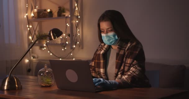 Молодая девушка в защитной маске и перчатках работает из дома онлайн, кашляет в защитной маске — стоковое видео