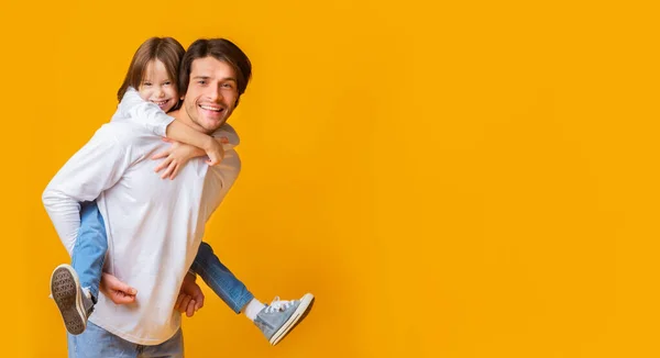 Smiling daddy and daughter posing over yellow background — Stock Photo, Image