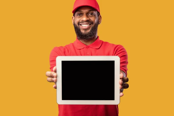 Courier mostrando tela do tablet recomendando serviço de entrega sobre fundo amarelo — Fotografia de Stock