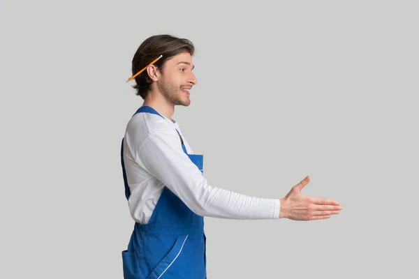 Arquitecto joven en uniforme de trabajo que da la mano para el apretón de manos, vista lateral —  Fotos de Stock