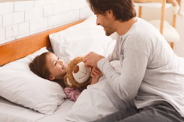 Ragazzina sdraiata a letto al mattino, abbracciando orsacchiotto — Foto Stock