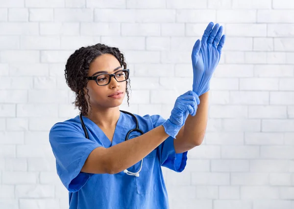 Afroamerikanische Tierärztin zieht im Tierkrankenhaus Gummihandschuhe an, leerer Raum — Stockfoto