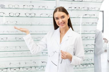 Kadın optometrist istemcinin gözlük seçmesine yardım ediyor