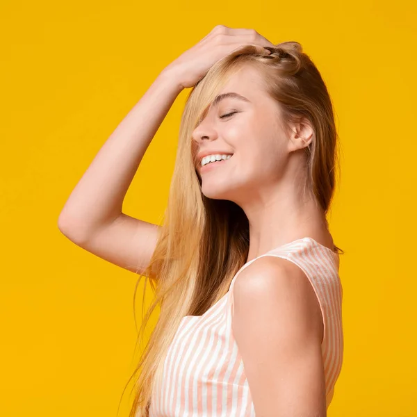 Dromerig jong meisje spelen met haar natuurlijke blond haar — Stockfoto