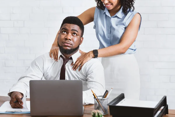No al acoso sexual. Afro americana dama haciendo hombro masaje a su molesto colega en el lugar de trabajo — Foto de Stock