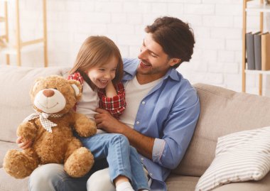 Baba küçük kızını gıdıklıyor, evde birlikte vakit geçiriyor.