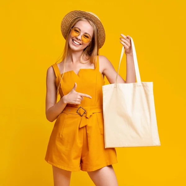 Veselý letní dívka drží bílý plátek taška a ukazuje na to — Stock fotografie