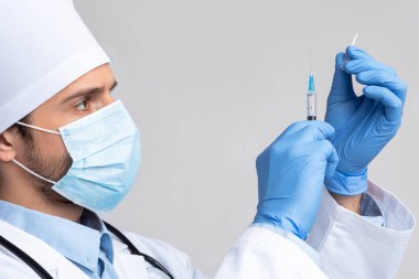 Profesyonel doktor şırıngayı aşıyla hazırlıyor.