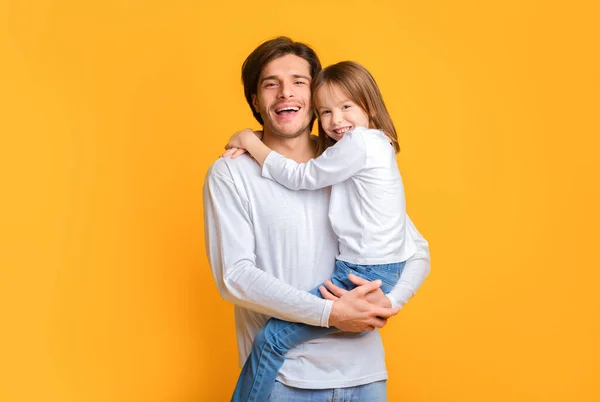 Padre e hija emocionales posando juntos sobre fondo amarillo —  Fotos de Stock