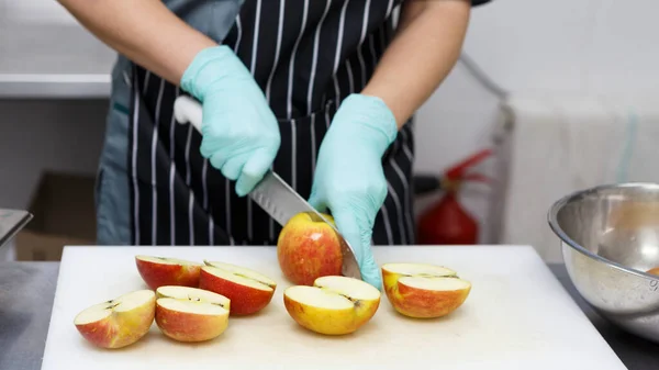 Frau in Gummihandschuhen schneidet Äpfel für gesunde Ernährung — Stockfoto