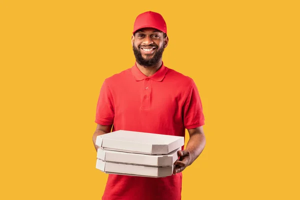 Pizzeria Courier Hombre entregando pizza de pie sobre fondo amarillo del estudio — Foto de Stock