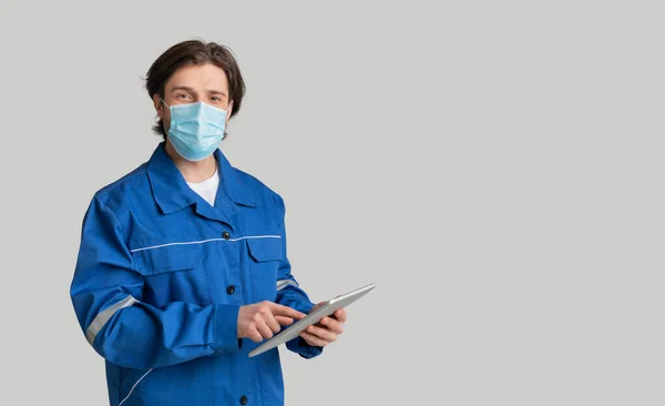 Młody inspektor ilościowy noszący maskę medyczną i korzystający z tabletu cyfrowego — Zdjęcie stockowe